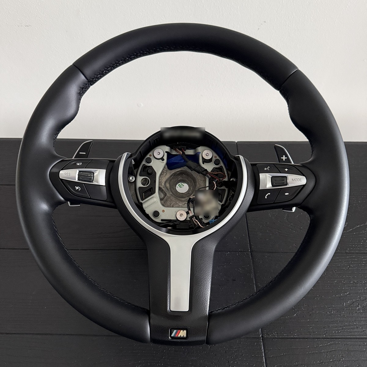 Same BMW M Sport steering wheel after restoration, deep matte black leather