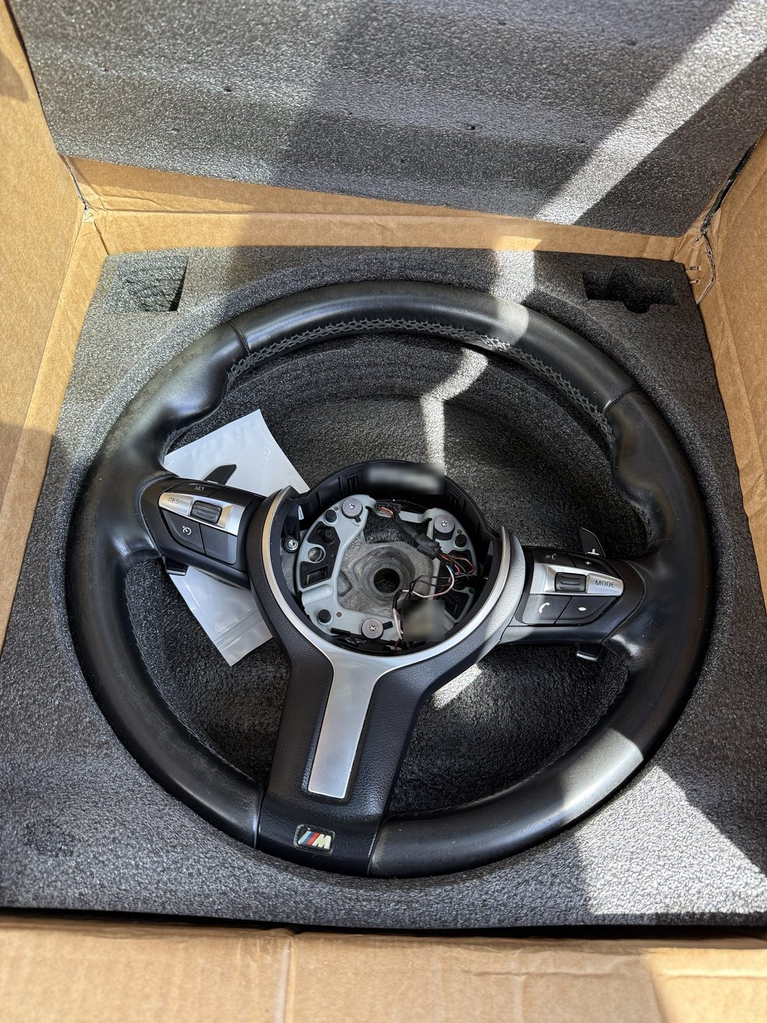 Worn leather BMW M Sport steering wheel in its shipping box before restoration