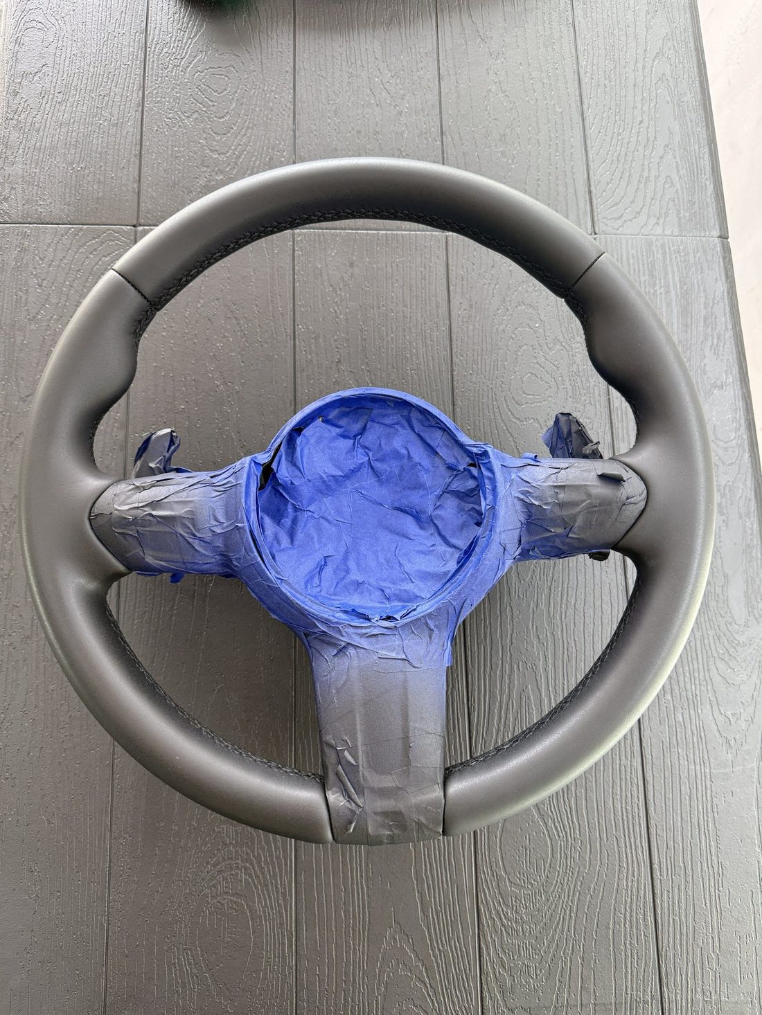 Steering wheel masked for refinishing with a fresh matte black finish on the rim